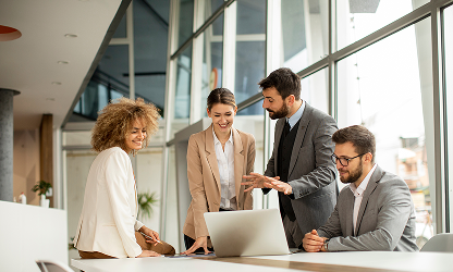 Group of well-dressed professionals in a well-lit office, gathered around a desk